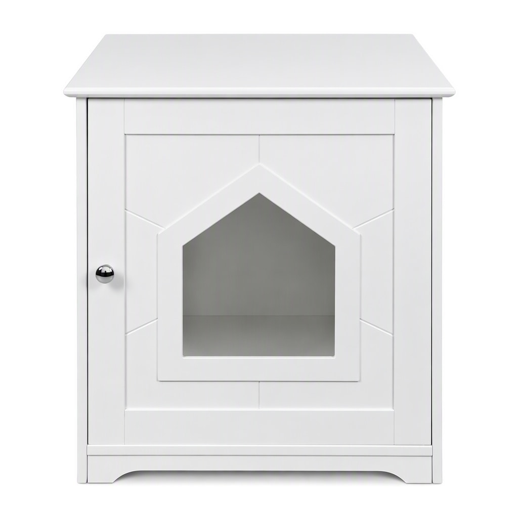 A cat investigating a white modern cat litter box enclosure featuring a unique cat-head shaped entrance, double-door panel design, and decorative wainscoting details. Used as a stylish side table with books and a vase.